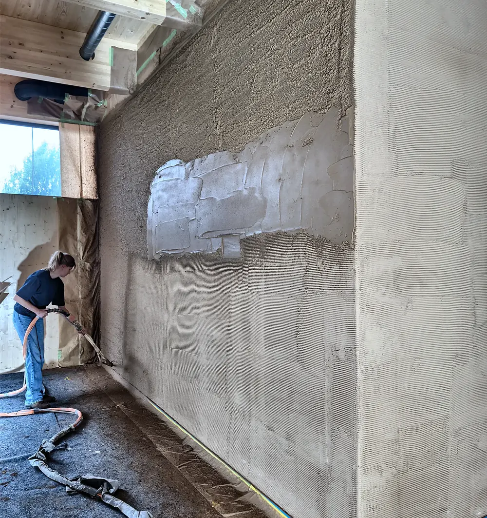 Leem wordt machinaal op een wand gespoten en daarna met de hand afgewerkt